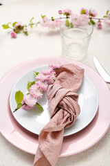 Beautiful table serving with cutlery, blooming tree branches and folded napkin on white grunge background