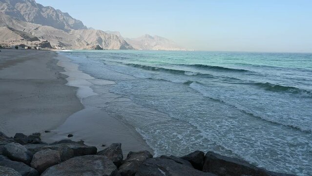 A 4K Video of  Waves Crashing on a Sandy Beach with Hajar Mountains in the background. Taken at Khasab Oman