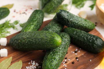 Wooden board with fresh cucumbers for preservation on table, closeup