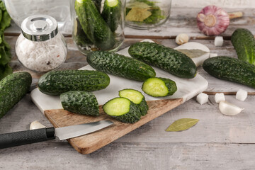 Board with fresh cut cucumbers for preservation on light wooden background