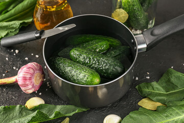 Saucepan with fresh cucumbers for preservation on dark background