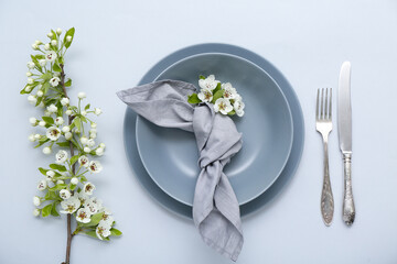Beautiful table setting with blooming tree branches on grey background
