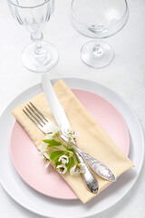 Beautiful table setting with blooming tree branch and glasses on white background