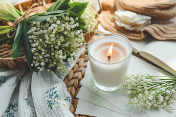 Obraz na płótnie Canvas A white burning candle and a bouquet of lilies of the valley, a natural spring photo