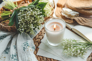 A white burning candle and a bouquet of lilies of the valley, a natural spring photo