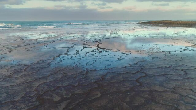Slow backward drone flight over beach with tidal pools at the Atlantic west coast of Portugal, Vila Nova de Milfontes