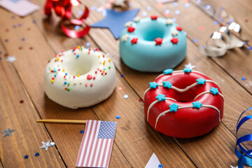 Fototapeta na wymiar Composition with donuts, USA flags and confetti on wooden table. Independence Day celebration