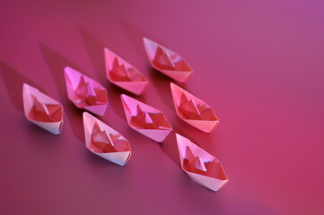 A group of paper boats on a purple background. Team. Direction of movement.