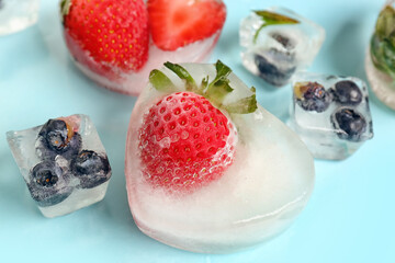 Fresh strawberry and blueberry frozen in ice on blue background