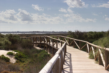 Fototapeta na wymiar Wooden bridge on the path of Punta del Boqueron next to the dunes of Camposoto beach; San Fernando; Cadiz; Andalusia; Spain.