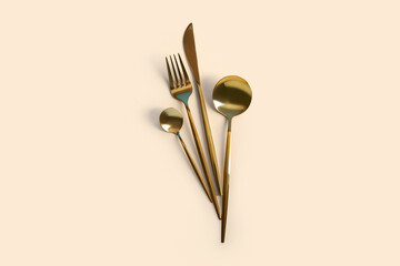 Golden cutlery on beige background