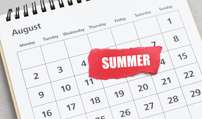 The word SUMMER on a small piece of paper and a calendar.