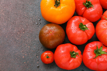 Different fresh tomatoes on dark background, closeup