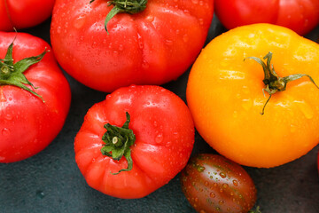 Different fresh tomatoes on dark background, closeup