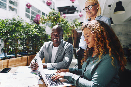 Diverse smiling businesspeople using a laptop