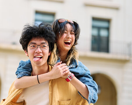 woman couple man happy hugging love young together piggyback travel tourist romantic hugging outside city vacation student smile fun relationship joy bonding