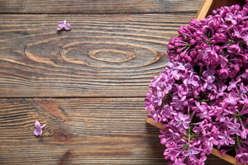 Box of beautiful lilac flowers on brown wooden background