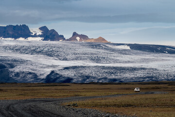 Car driving on gravel road in Iceland - view of Icelandic nature and mountains, glacier and Vatnajökull National Park