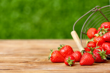 Basket with fresh strawberry on wooden table outdoors