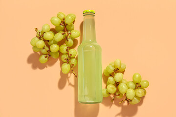 Composition with bottle of fresh soda and grapes on beige background