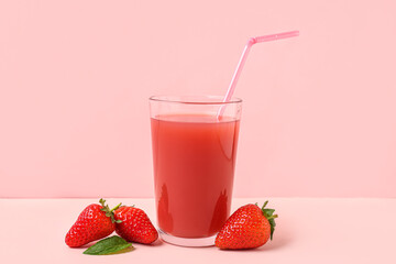 Glass of tasty strawberry juice on white table against pink background