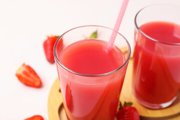 Board with glasses of tasty strawberry juice on white table