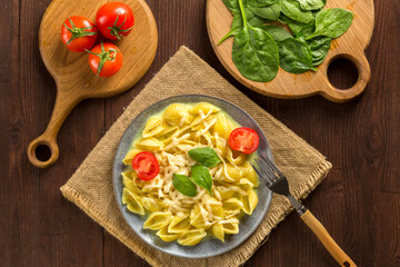 Pasta in a creamy sauce with cheese next to the planks of tomatoes, a knife and herbs.