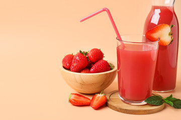 Bottle and glass of tasty strawberry juice on orange background