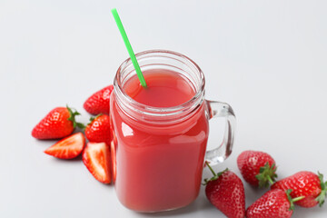 Mason jar of tasty strawberry juice on grey background