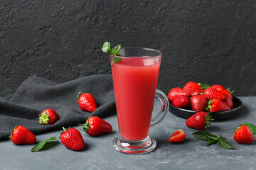 Glass of juice and plate with strawberry on blue table