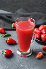 Glass of juice and plate with strawberry on blue table