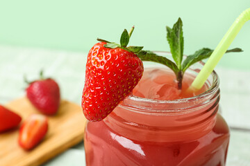 Mason jar of tasty strawberry juice green wooden table