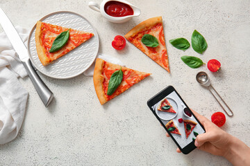 Woman taking photo of tasty pizza margarita on white grunge background