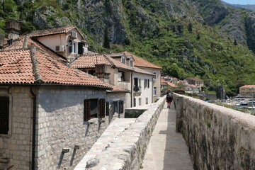 Fototapeta na wymiar Fortress wall in Kotor, Montenegro. Kotor is a beautiful historic city on the Unesco list. Silhouettes of walking people on wall.
