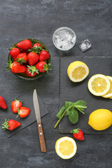 Composition with ripe strawberry, lemon and mint on dark background