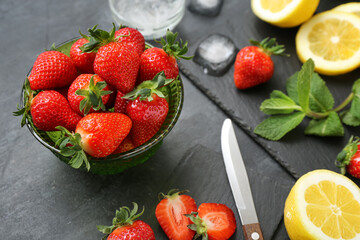 Bowl with ripe strawberry, lemon and mint on dark background, closeup