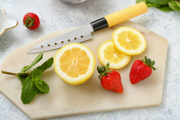 Board with ripe strawberry, lemon slices and mint on light background, closeup