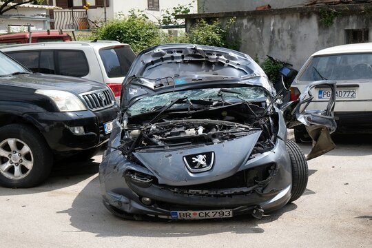 Kotor, Montenegro - circa May 2023: Black destroyed Peugeot  after an accident stands between cars in the yard 