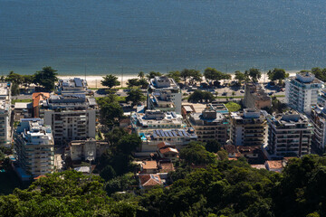 Edge of Praia de Charitas, in Niterói, Rio de Janeiro, Brazil. Buildings and houses in front of the beach, surrounded by nature. Sunny day