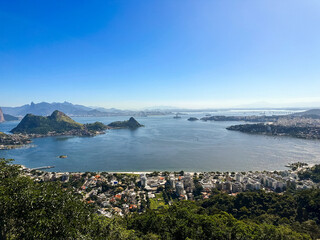 Beautiful view of Rio de Janeiro, Brazil seen from Niterói. With many hills in the background, Guanabara Bay, Jujuruba, Rio Niterói Bridge, Christ the Redeemer, beaches, pier with a boat. Sunny day