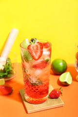 Glass of delicious strawberry mojito on color background