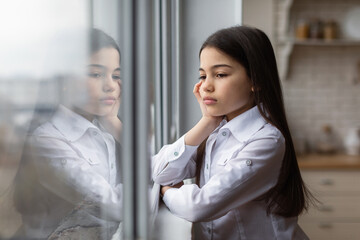 Unhappy Girl Looking Out Window Suffering From Depression At Home