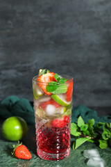 Glass of delicious strawberry mojito on dark background