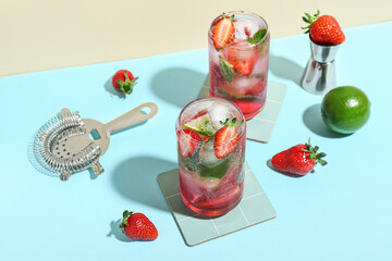 Glasses of delicious strawberry mojito on color background