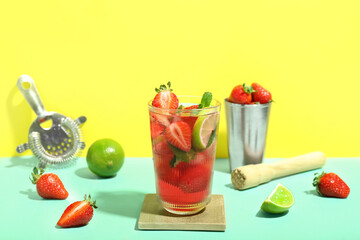 Glass of delicious strawberry mojito on color background