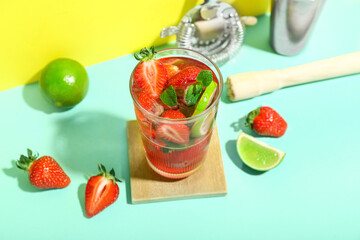Glass of delicious strawberry mojito on color background