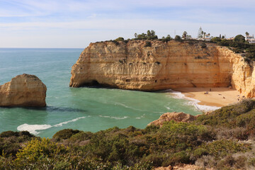 Fototapeta na wymiar Limestone rock cliffs and rock in the Atlantic Ocean with a small sandy beach on a sunny winter day along the Seven Hanging Valleys Trail in southern Portugal.