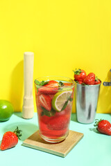 Glass of delicious strawberry mojito on color background