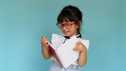 Girl with book. Smart appearance with glasses. The child is reading a book on blue background. Happy schoolgirl with a book. Clever girl is reading a book.