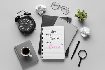 Notebooks with question ARE YOU READY FOR EXAMS?, cup of coffee and alarm clock on grey background